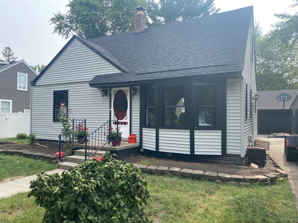 Story-and-a-half Mount Clemens home with white lap siding, black window trim and a dark charcoal shingle roof