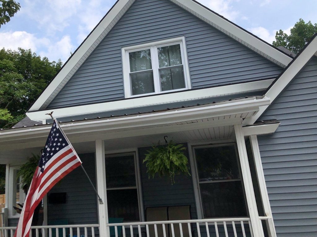 Mount Clemens home with blue-gray lap siding, white gable trim, white vented soffit and a white front porch
