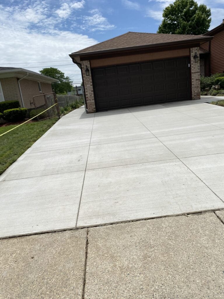 New concrete driveway with saw-cut control joints leading to a two-car garage on Canterbury Drive in Sterling Heights, MI