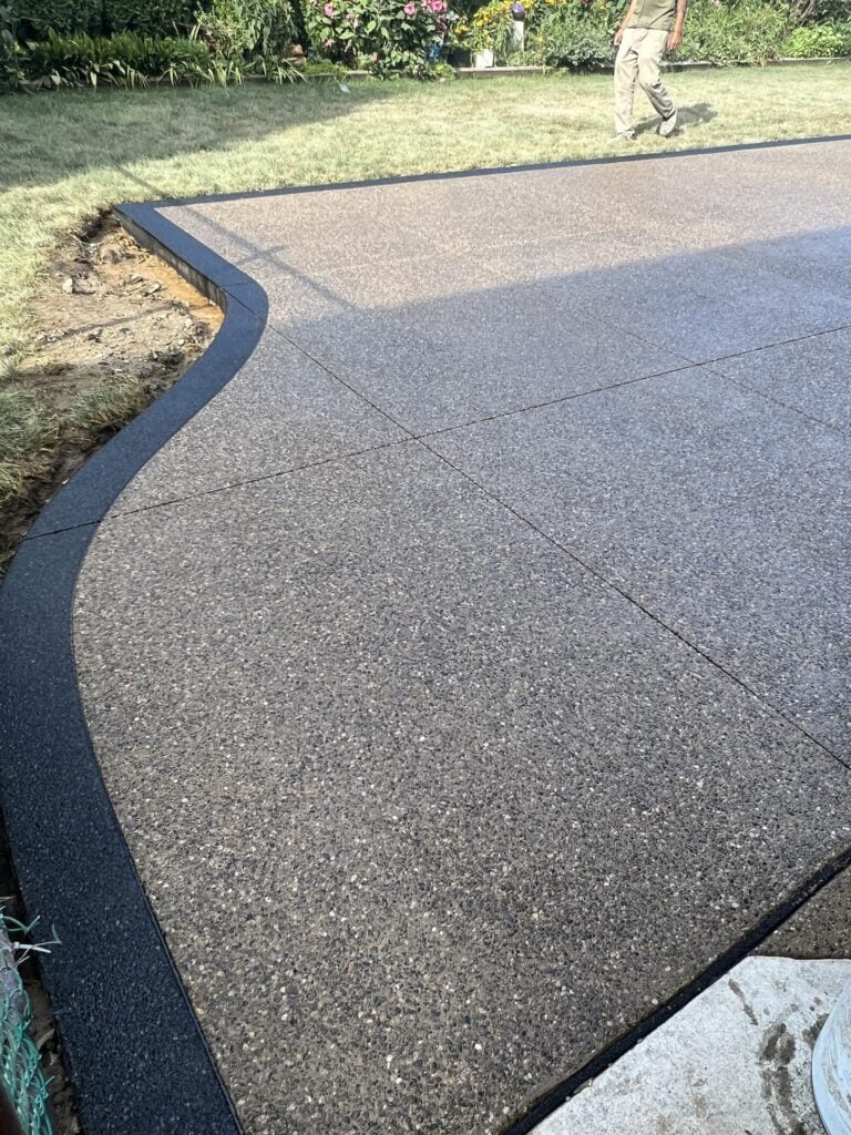Curved exposed aggregate concrete patio with a dark border on South Colonial Court in St. Clair Shores, MI