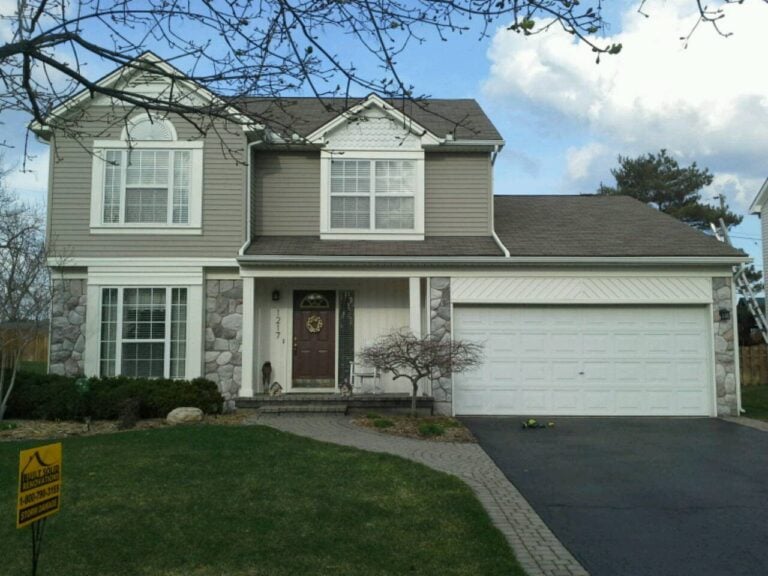 Two-story stone and sided home with a new shingle roof and Rock Solid yard sign on Quail Ridge Drive in Oxford, MI