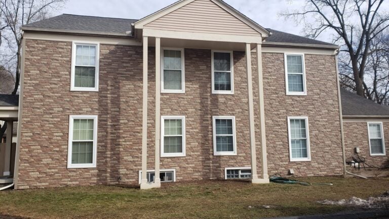 Two-story home with white columns and tan gable siding after a roofing and siding project on 1st Street in Rochester, MI