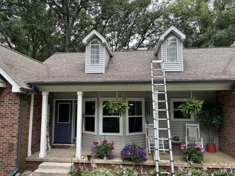 Cape Cod-style home with twin dormers, a shingle roof and a ladder at the porch on Cedar Island Road in White Lake, MI