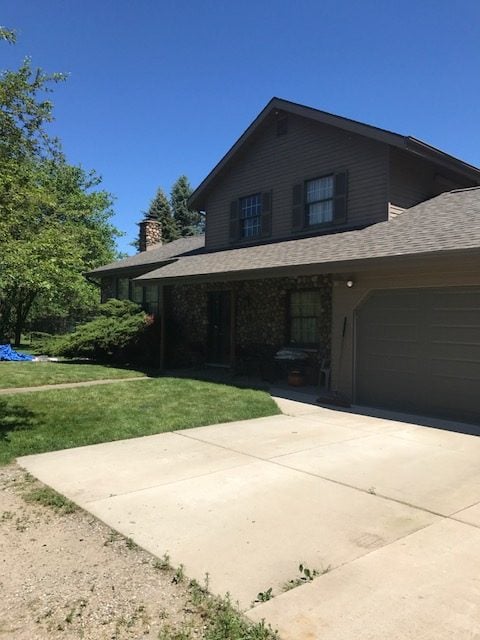 Two-story home with a shingle roof and attached garage on Hicks Road in Armada, MI