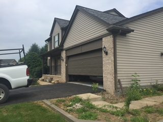 Two-story sided home with a dark shingle roof and brick-trimmed garage on Kesterel Ridge Road in Brighton, MI