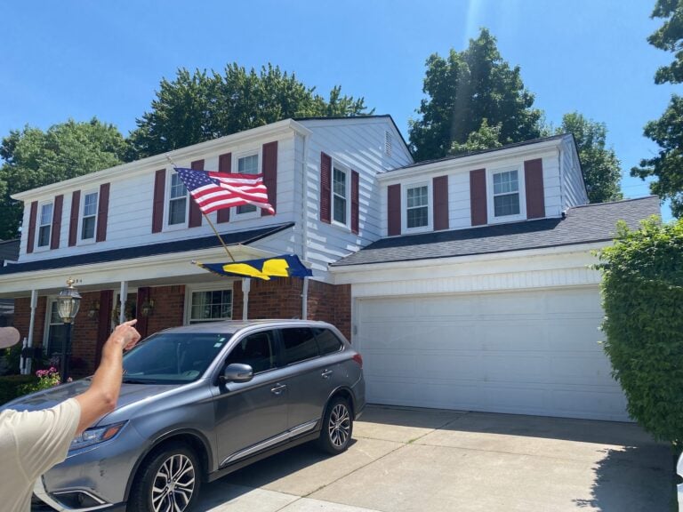Two-story home with new white siding and red shutters above an attached garage on Danbury Lane in Harper Woods, MI