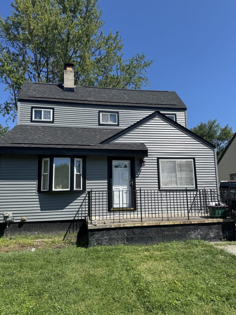 Two-story home with new gray lap siding and black window trim on East 12 Mile Road in Roseville, MI