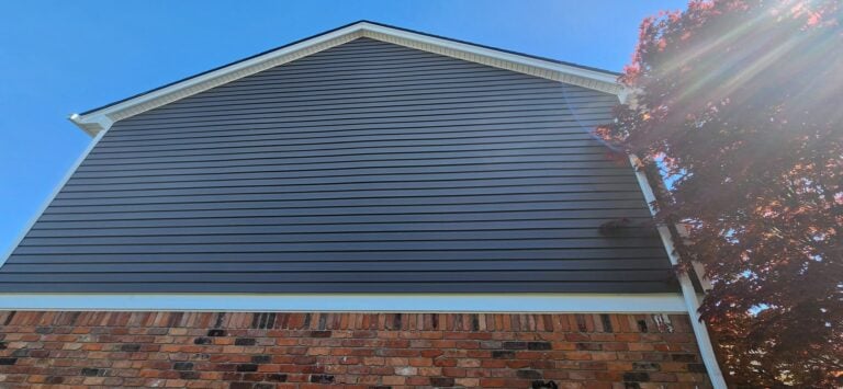 Side gable of a home with new dark blue lap siding and white trim above brick on Foxtail Court in Macomb Township, MI