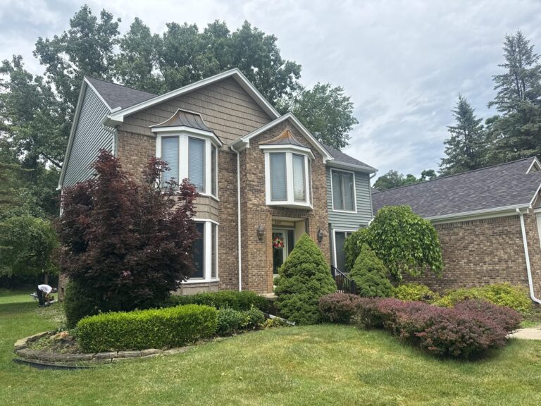 Two-story brick home with shake-style gable siding and bay windows on Norfolk Court in Shelby Township, MI