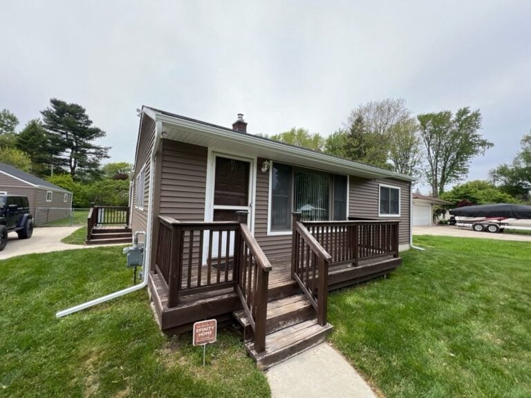 Cottage-style ranch with new brown lap siding and a wood deck entry on Willowmere Street in Harrison Township, MI